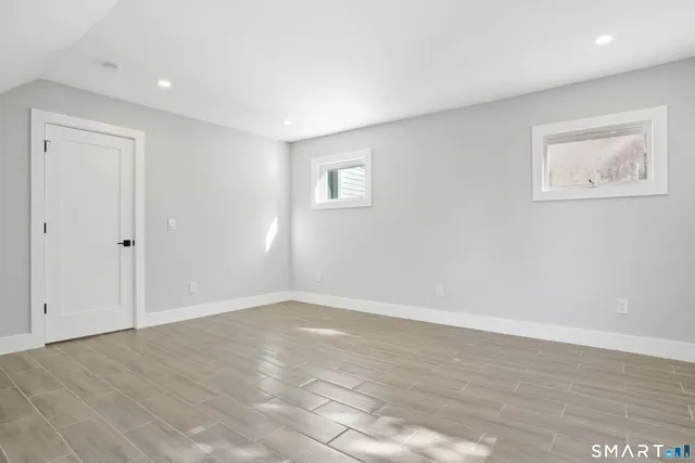 a view of an empty room with wooden floor and window