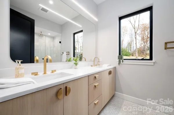 a bathroom with a double vanity sink and mirror with window