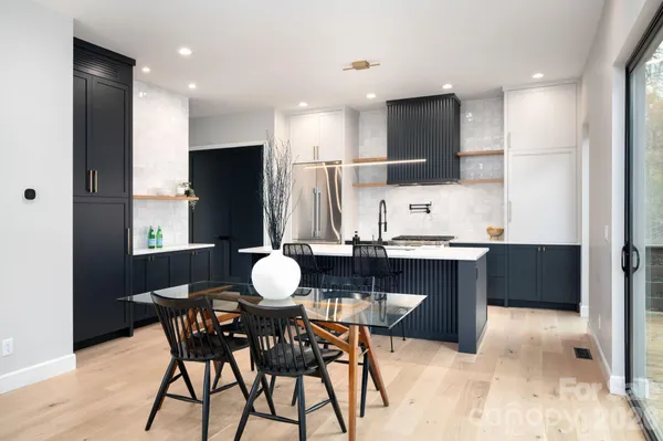 a kitchen with stainless steel appliances kitchen island granite countertop a table chairs sink and cabinets