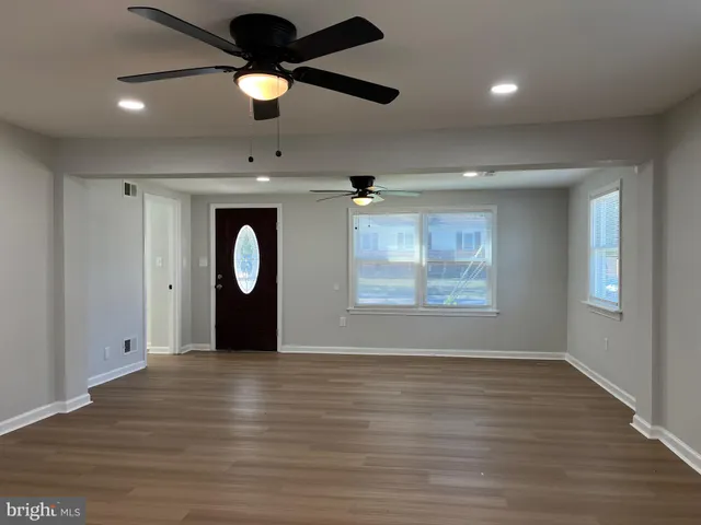a view of an empty room with window and wooden floor