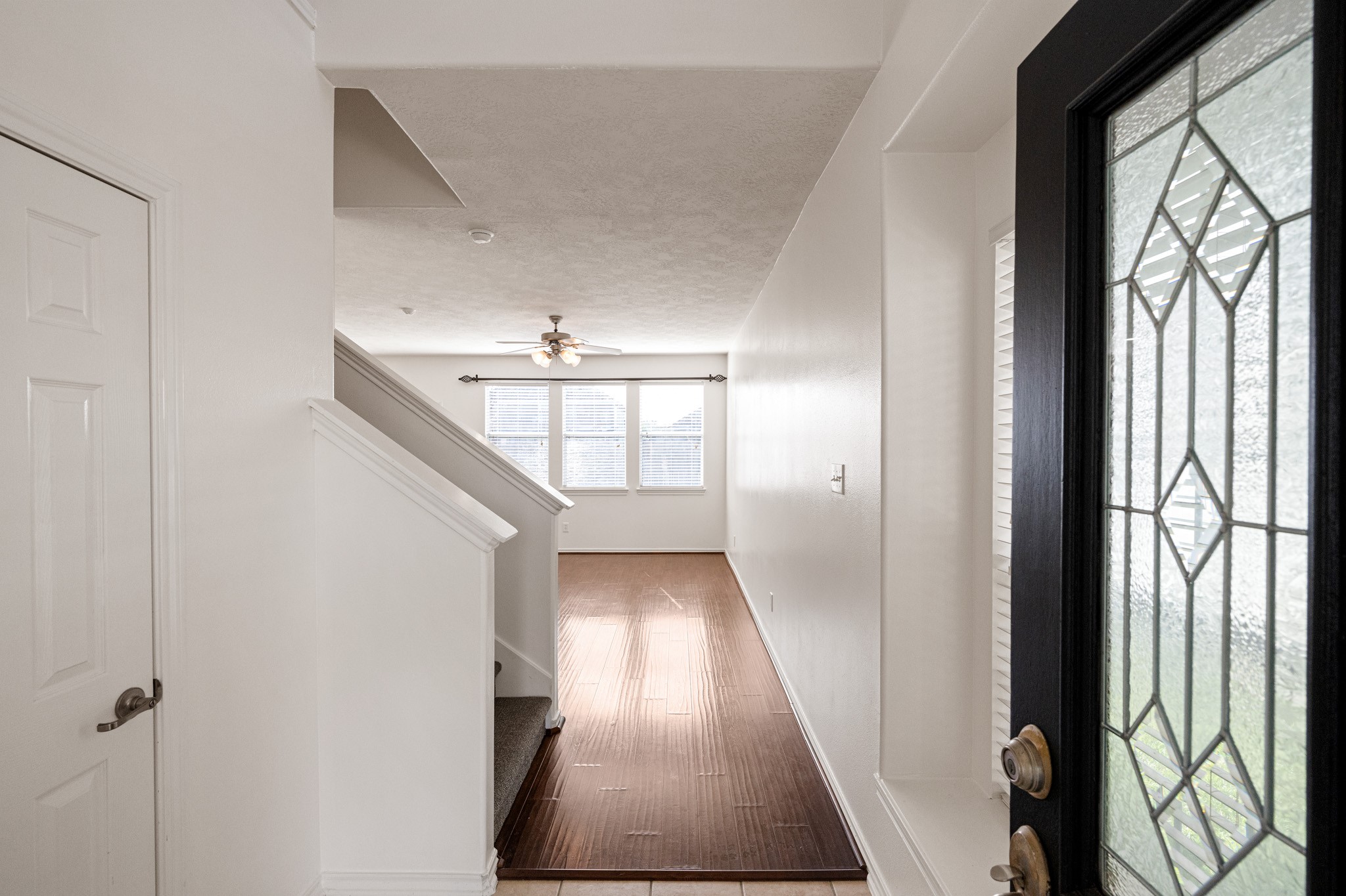 Welcome home to a bright and inviting entryway featuring elegant flooring, a stylish ceiling fan, and ample natural light streaming through large windows, setting the stage for a warm and welcoming living space.