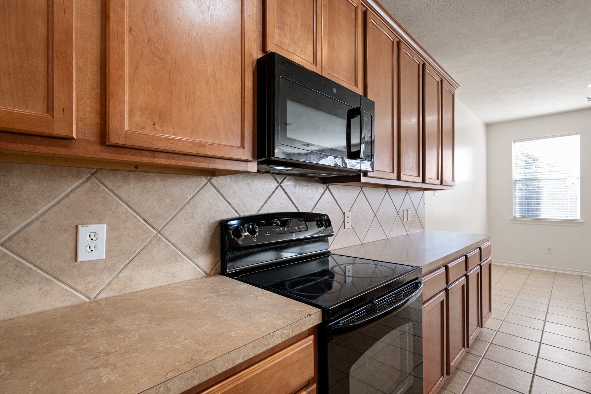 11938 Ramla Place Trail Houston, TX 77089 - Photo 11 of 28 This inviting kitchen features warm wooden cabinets, appliances, and ample counter space, all bathed in natural light from a bright window.