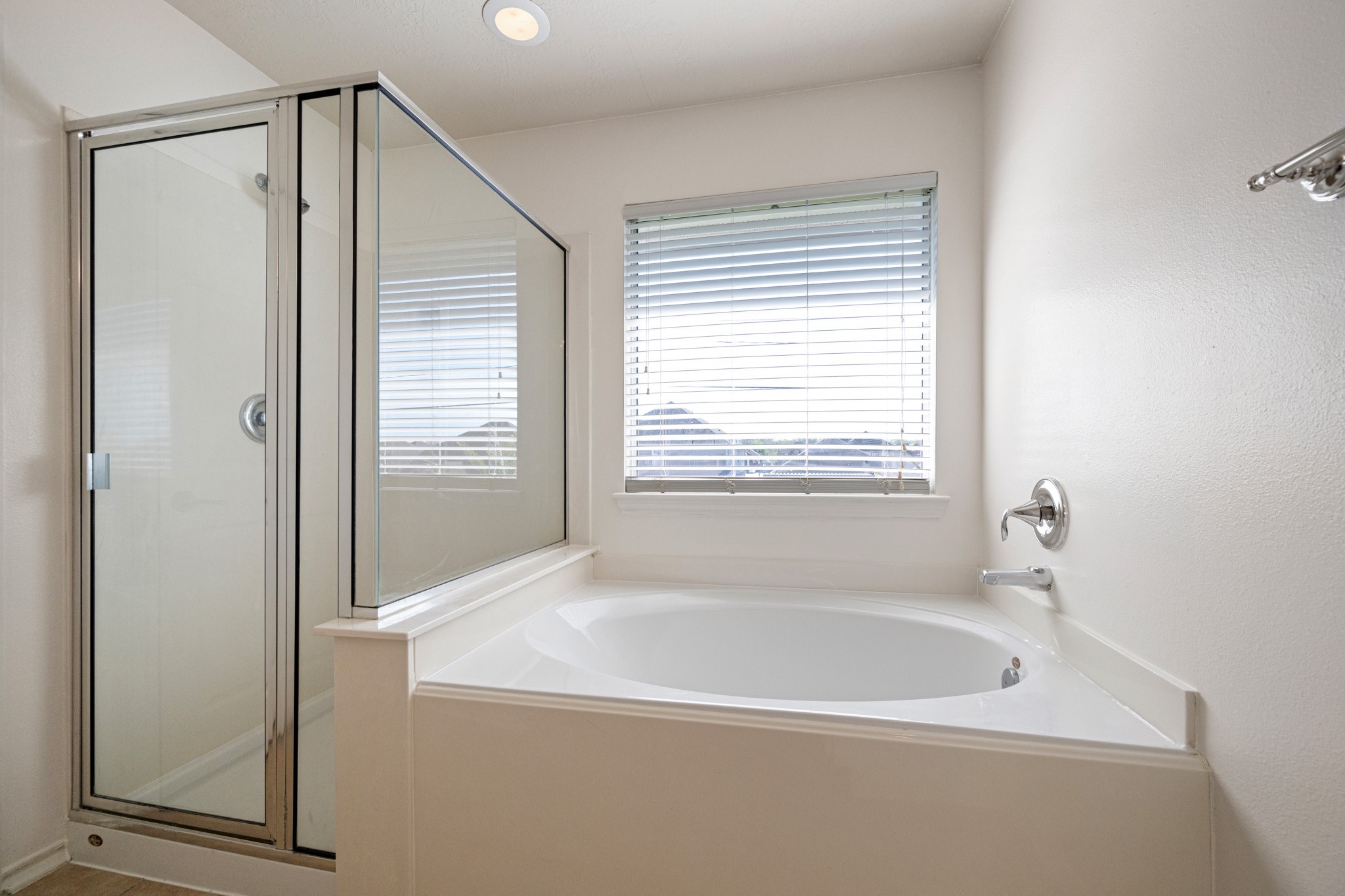 11938 Ramla Place Trail Houston, TX 77089 - Photo 20 of 28 This inviting primary bathroom features a sleek glass shower and a luxurious soaking tub, all bathed in natural light from a large window, creating a serene oasis for relaxation.