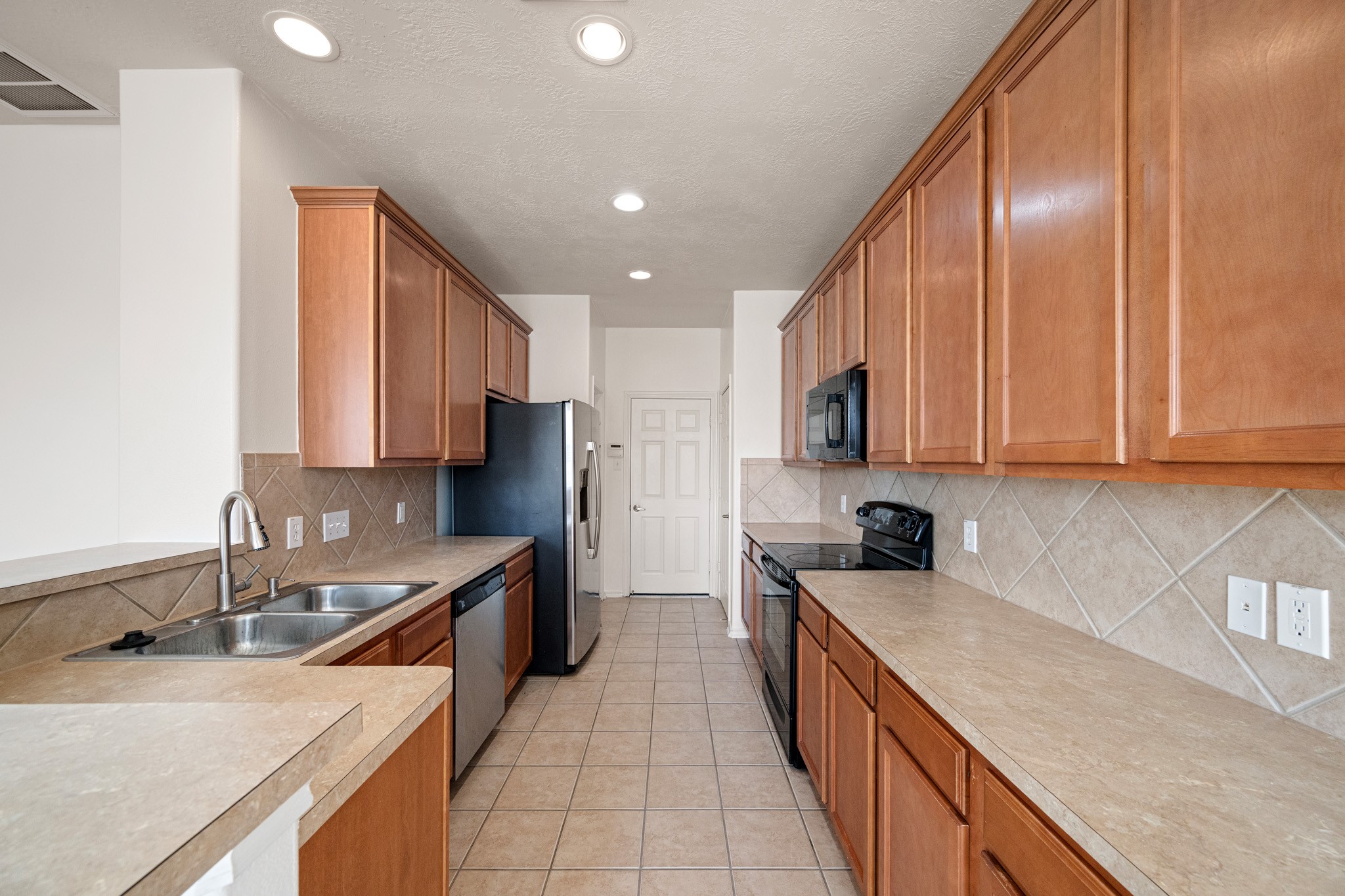 11938 Ramla Place Trail Houston, TX 77089 - Photo 7 of 28 This kitchen offers a warm, inviting space with sleek countertops, ample wooden cabinetry, and modern stainless steel appliances, perfect for culinary creativity.