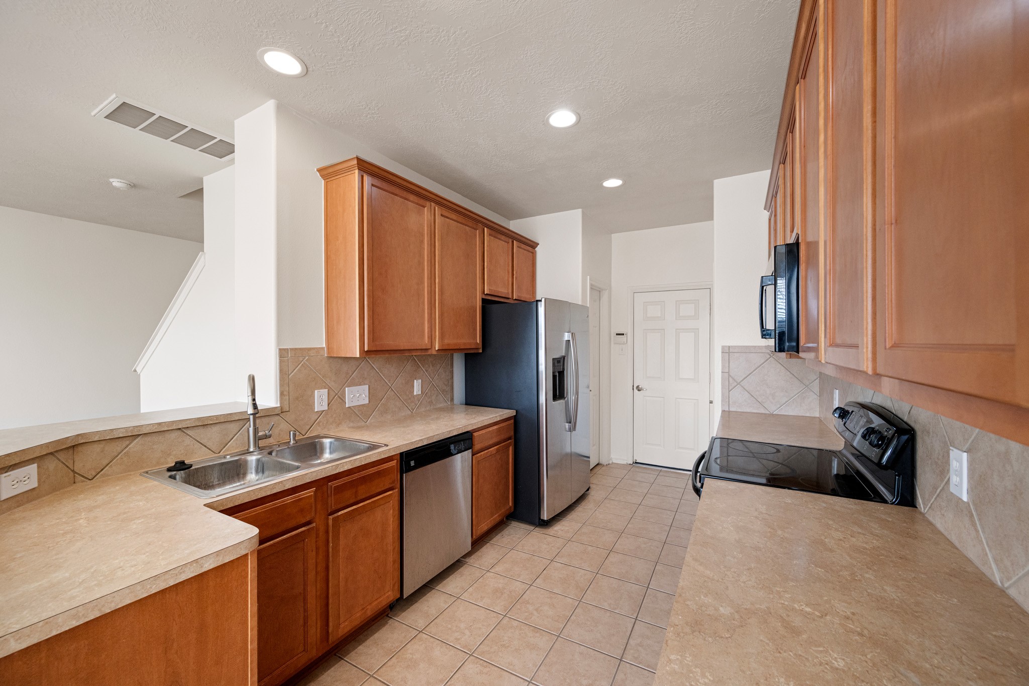 11938 Ramla Place Trail Houston, TX 77089 - Photo 8 of 28 Discover culinary bliss in this sleek kitchen, featuring appliances, warm wooden cabinetry, and expansive counter space perfect for both everyday meals and entertaining guests.