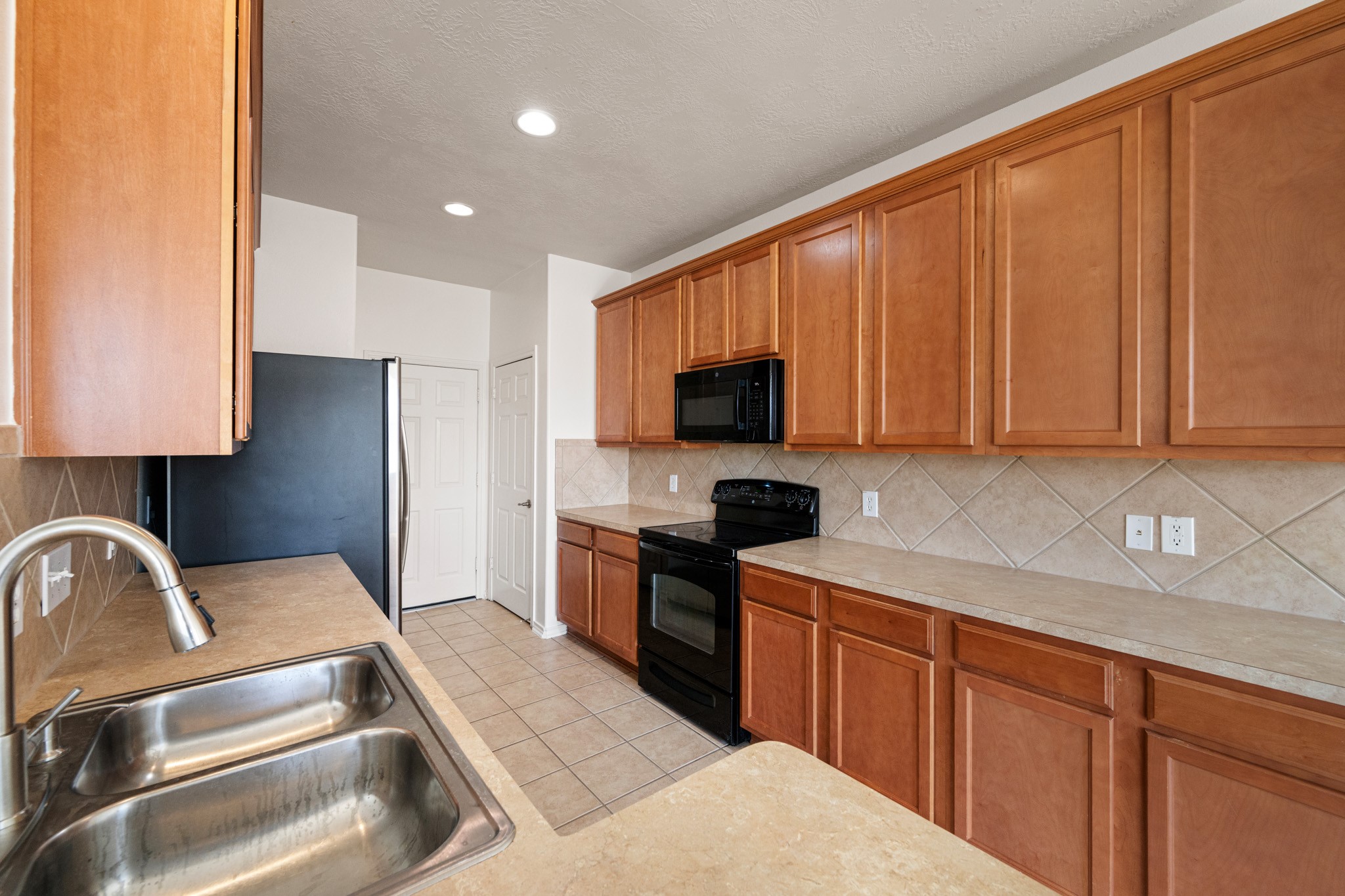 11938 Ramla Place Trail Houston, TX 77089 - Photo 9 of 28 This inviting kitchen boasts warm wood cabinetry, appliances, and ample countertop space, perfect for cooking and entertaining.