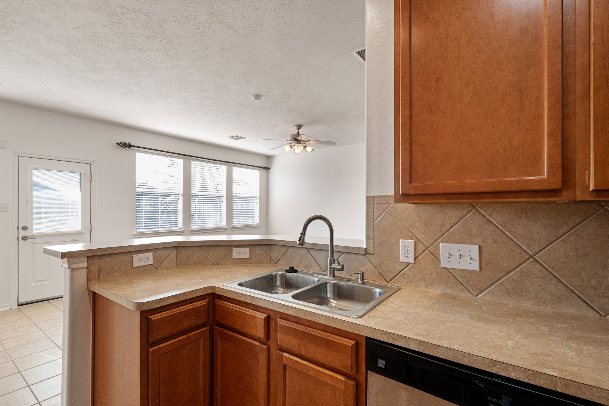 11938 Ramla Place Trail Houston, TX 77089 - Photo 10 of 28 This inviting kitchen features warm wood cabinetry, a sleek countertop with a double sink, and ample natural light streaming through wide windows, creating a perfect space for culinary creativity and entertaining.