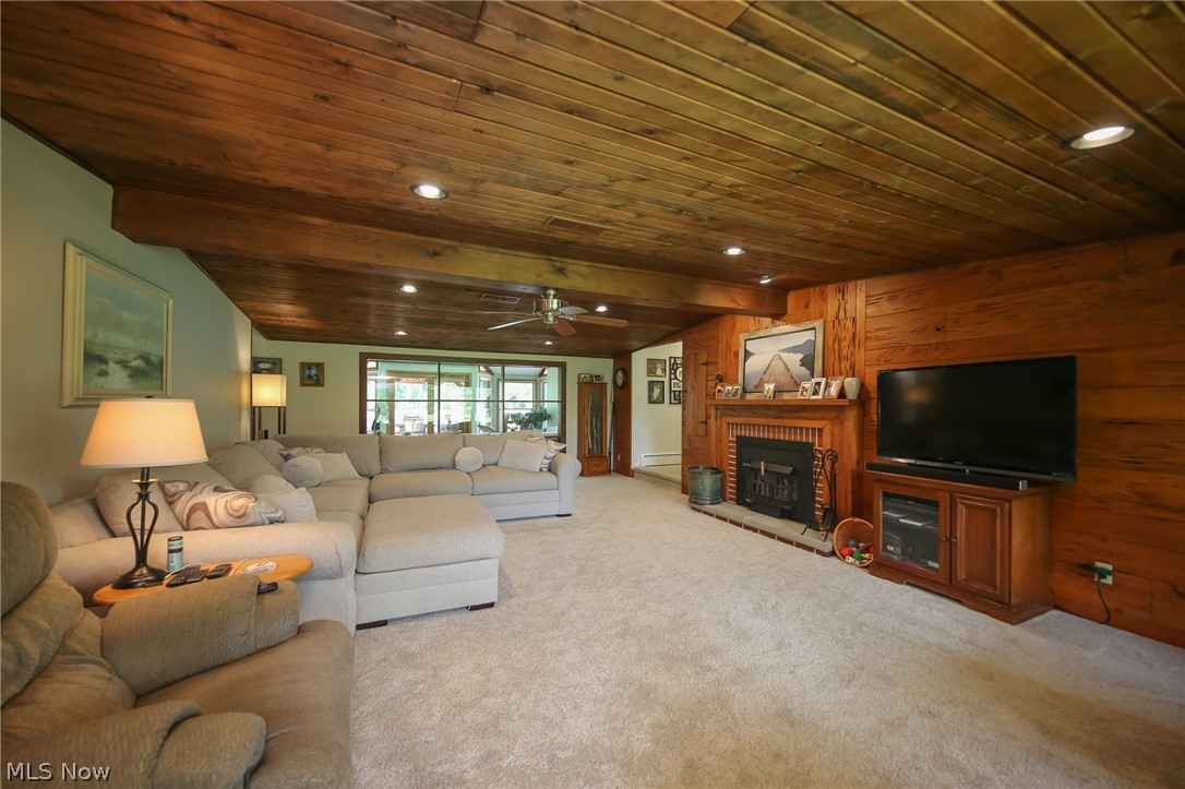 3362 Granger Road Medina, OH 44256 - Photo 5 of 49 Carpeted living room featuring wooden ceiling, a fireplace, wooden walls, and ceiling fan