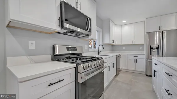 a kitchen with stainless steel appliances a stove a microwave and white cabinets