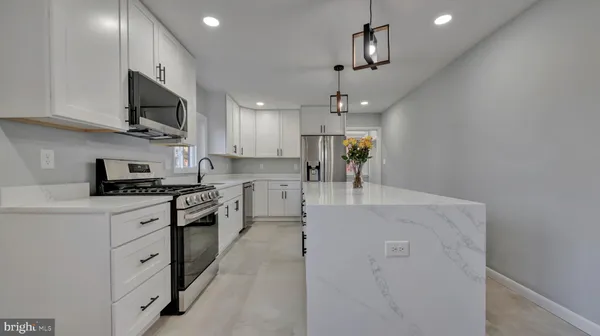 a large kitchen with stainless steel appliances granite countertop a sink dishwasher a stove and a refrigerator with wooden floor