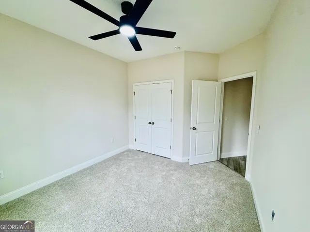 an empty room with a ceiling fan and carpet