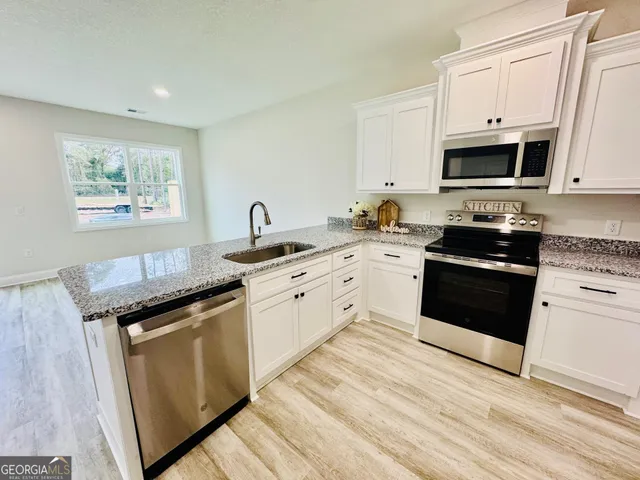 a kitchen with stainless steel appliances granite countertop a stove a sink and a microwave