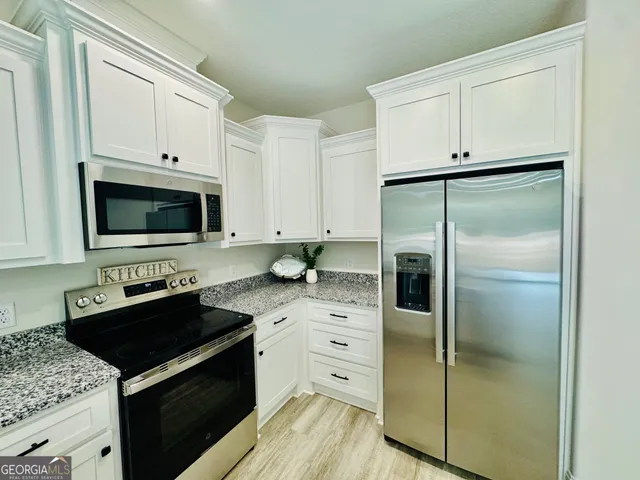 a kitchen with white cabinets and appliances