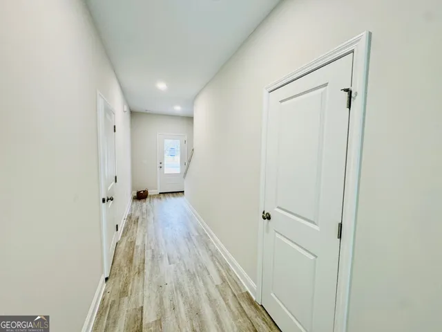 a view of a hallway with wooden floor and a bathroom