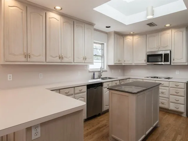 a kitchen with stainless steel appliances granite countertop a sink a stove and cabinets