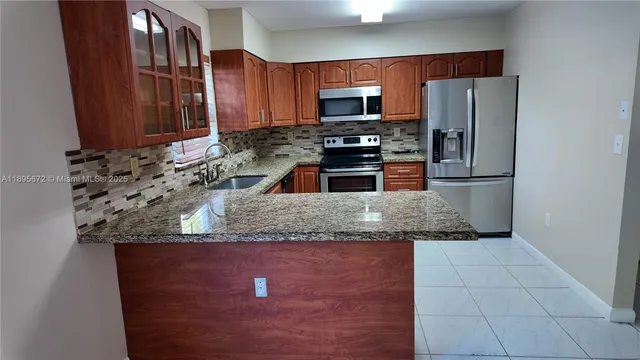 a kitchen with granite countertop a refrigerator and a stove top oven