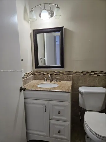 a bathroom with a granite countertop toilet sink and mirror