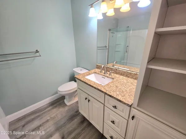 a bathroom with a granite countertop sink a toilet and a mirror