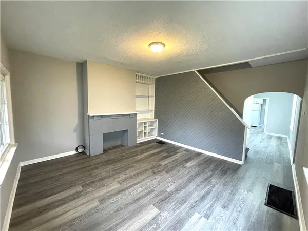 a view of empty room with wooden floor and fireplace