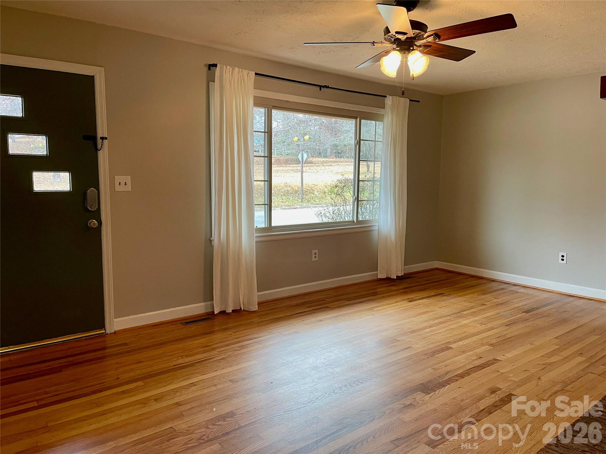 635 Powell Road Northeast Lenoir, NC 28645 - Photo 4 of 48 an empty room with wooden floor fan and windows