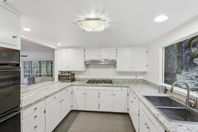 a kitchen with granite countertop a sink stainless steel appliances and cabinets
