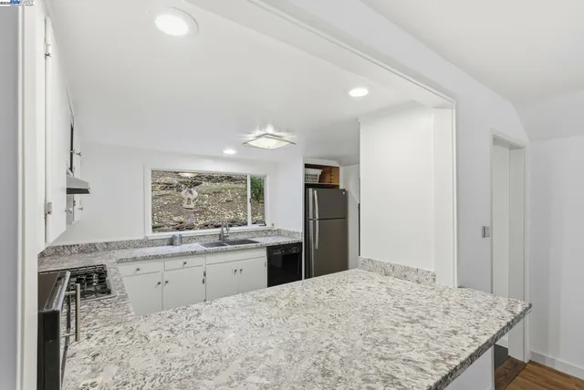 a kitchen with granite countertop a sink stove and refrigerator