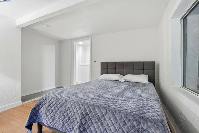 a large bed sitting in a bedroom next to a window and a wooden floor