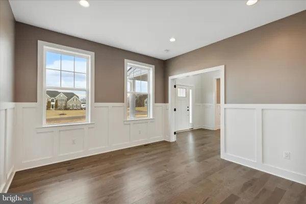 an empty room with wooden floor fireplace and windows