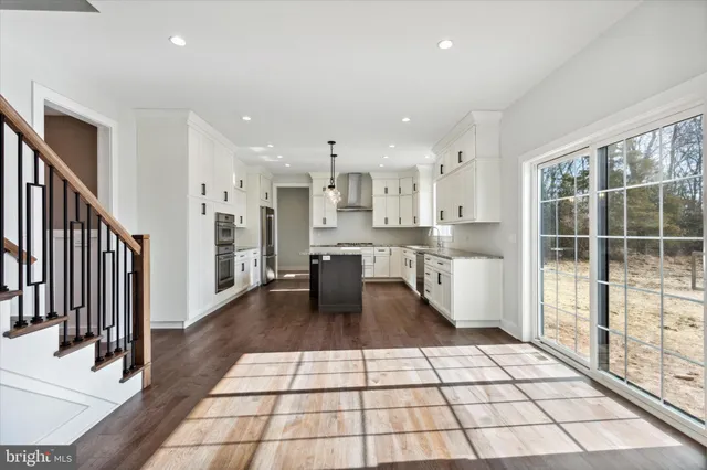 a kitchen with a stove center island wooden floor cabinets and a chandelier