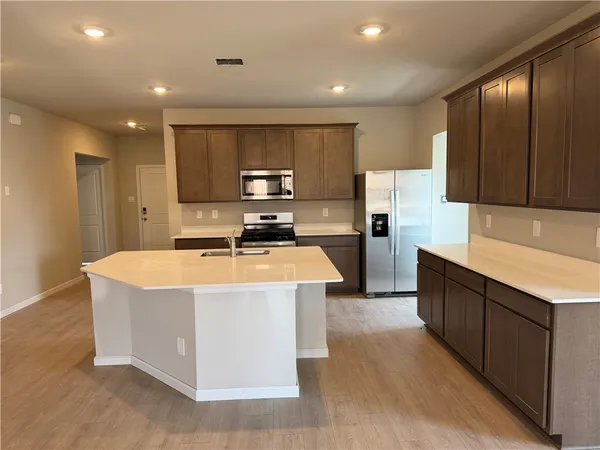 a kitchen with stainless steel appliances a sink a stove a refrigerator cabinets and a kitchen island