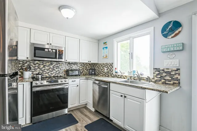 a kitchen with granite countertop white cabinets and stainless steel appliances