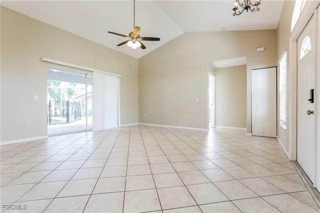 a view of an empty room and window and chandelier fan