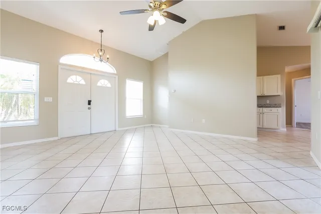 a view of an empty room and window and chandelier fan