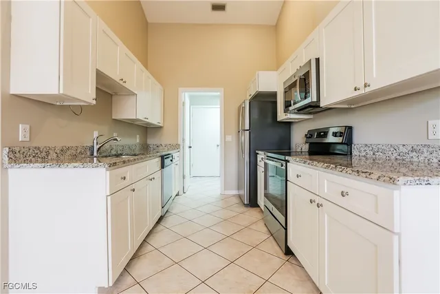 a kitchen with stainless steel appliances granite countertop a sink and dishwasher a stove top oven with white cabinets