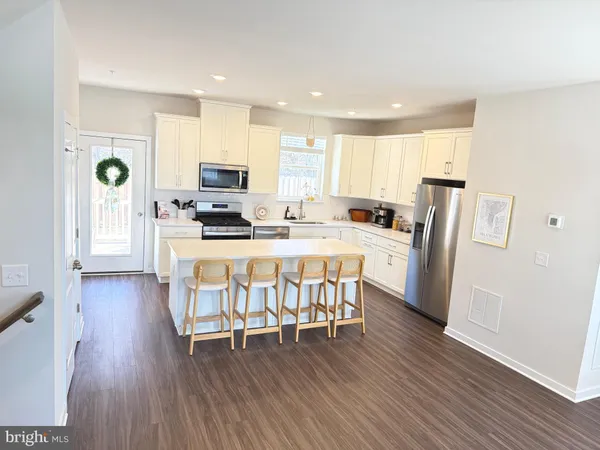 a kitchen with stainless steel appliances kitchen island granite countertop wooden floors and white cabinets