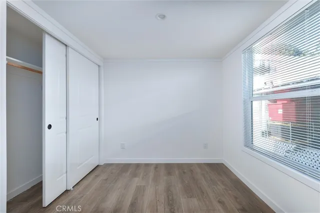 a view of an empty room with a window and wooden floor