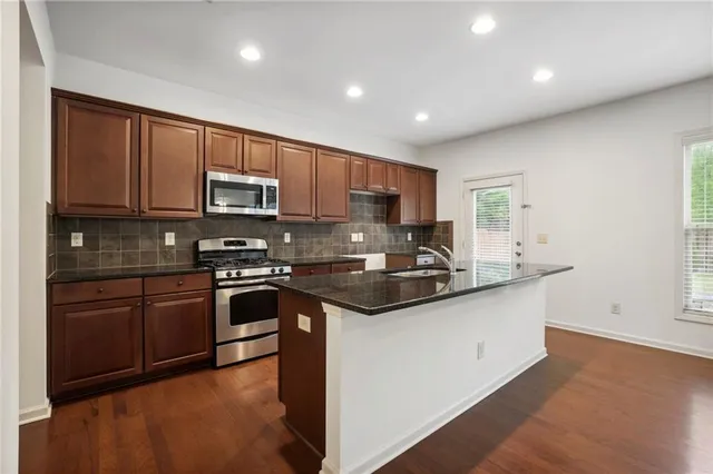 a kitchen with stainless steel appliances granite countertop a stove a sink and a microwave