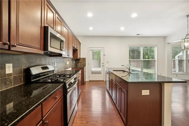 a kitchen with stainless steel appliances granite countertop a stove a sink and a microwave