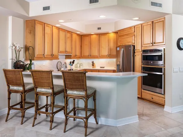 a kitchen with stainless steel appliances a table chairs refrigerator and sink