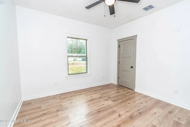 an empty room with a window and a ceiling fan