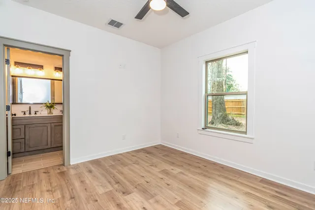 a view of an empty room with a window and a kitchen