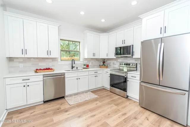 a kitchen with white cabinets white appliances and sink