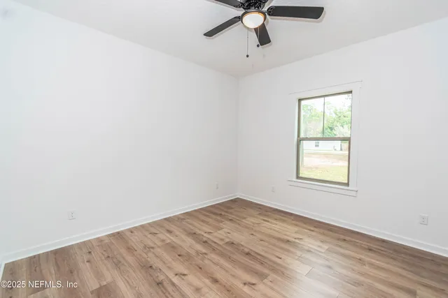 an empty room with a window and a fan