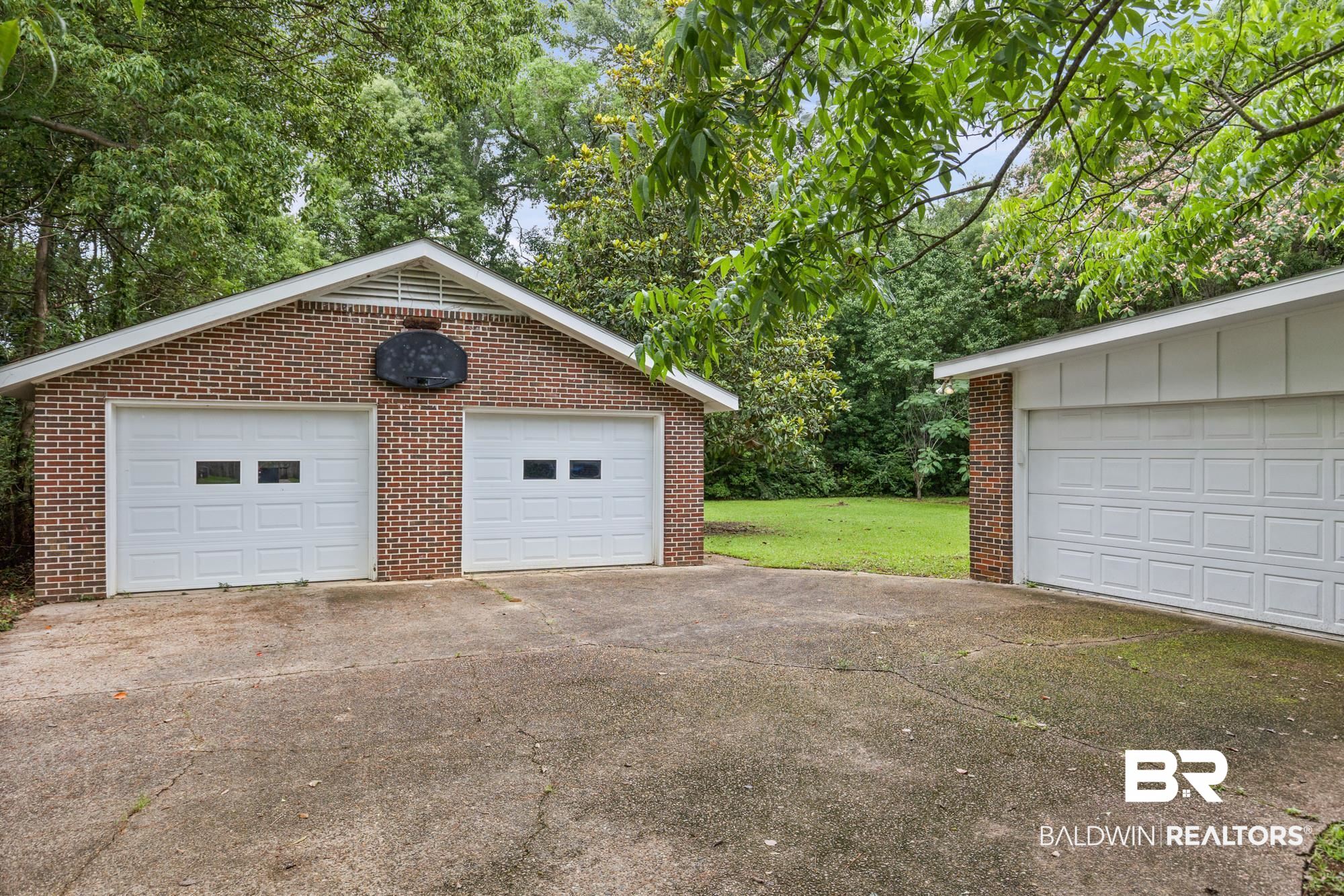 312 Sutherland Drive Mobile, AL 36611 - Photo 25 of 28 Brick exterior two-car garage with white paneled doors and window accents, complemented by an additional single-car garage