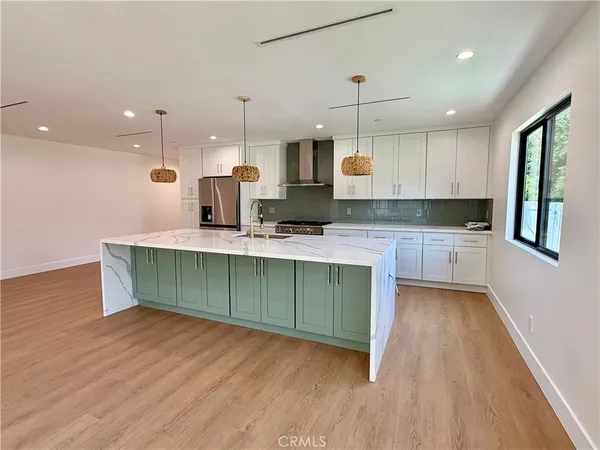 a kitchen with kitchen island granite countertop a sink cabinets and wooden floor