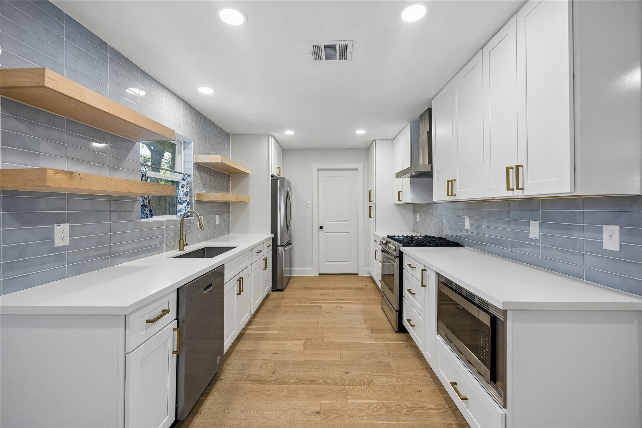 4725 Spellman Road Houston, TX 77035 - Photo 10 of 22 Thoughtfully renovated kitchen boasts quartz counters, stylish subway tile backsplash, SS appliances & the latest fininshes! Door leads to updated laundry room.