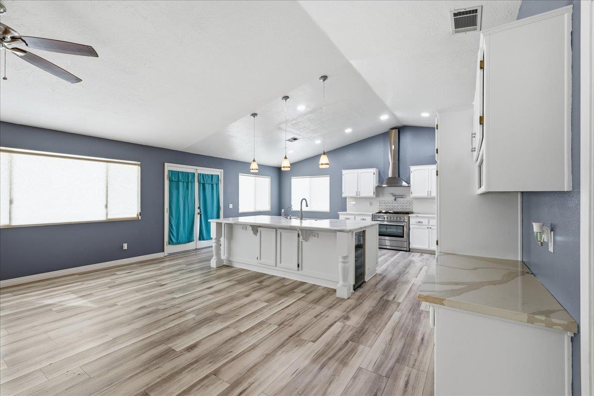 15358 Lookout Road Apple Valley, CA 92307 - Photo 23 of 30 a large white kitchen with kitchen island a sink dishwasher a stove and a refrigerator with wooden floor