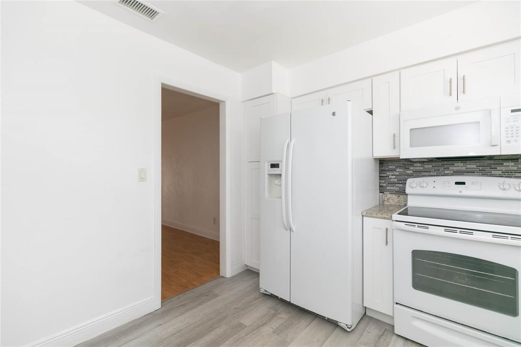 7531 Abonado Road, Unit 1 Tampa, FL 33615 - Photo 11 of 26 a view of a kitchen with white cabinets and wooden floor