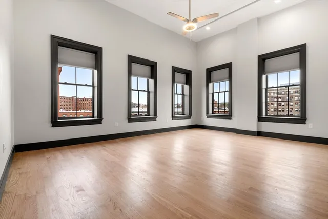a view of an empty room with window and wooden floor