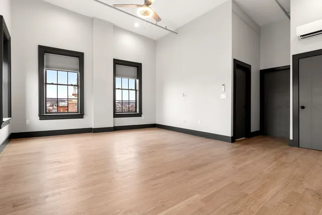 an empty room with wooden floor and windows
